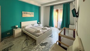A bedroom with a bed, nightstands, a chair, a painting, and a view of the outdoors.