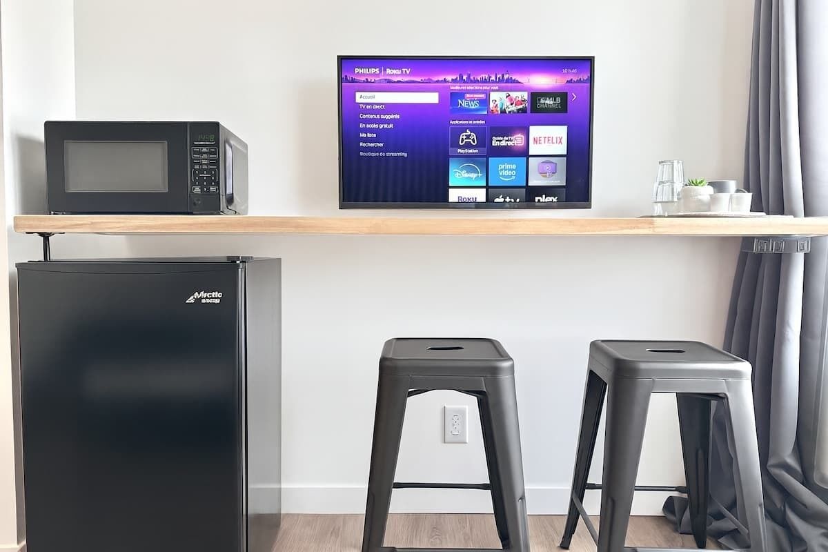Una kitchenette moderna equipada con microondas, refrigerador y dos taburetes.