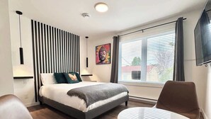 Une chambre moderne avec un lit, des tables de chevet, un bureau et une fenêtre avec des rideaux.