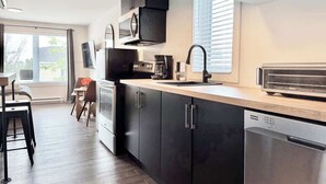 Une cuisine moderne avec des meubles de couleur noire, un four encastré, un grille-pain et un lave-vaisselle.