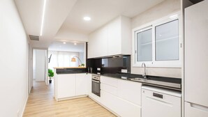 Une cuisine moderne avec des meubles blancs, un plan de travail noir et un lave-vaisselle encastré.