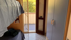 Una habitación con una cama, un armario y un ventanal corredera que da a un espacio exterior.