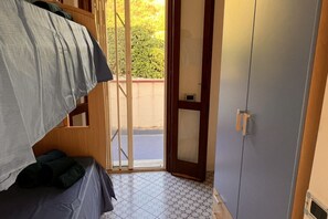 A room with a bed, a wardrobe, and a sliding glass door leading to an outdoor area.