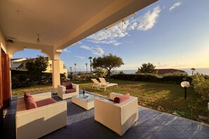 An outdoor seating area with wicker furniture and a view of the sea.