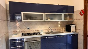 Una cocina compacta con armarios azul oscuro, horno empotrado, estufa a gas y un lavabo.