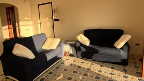 A living room with two sofas, a patterned floor, a door, and a small table.