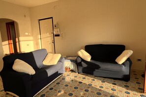 Een woonkamer met twee banken, een vloer met patroon, een deur en een kleine tafel.