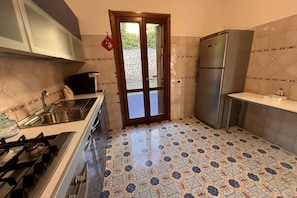 A kitchen with a gas stove, sink, refrigerator, and patterned floor tiles.