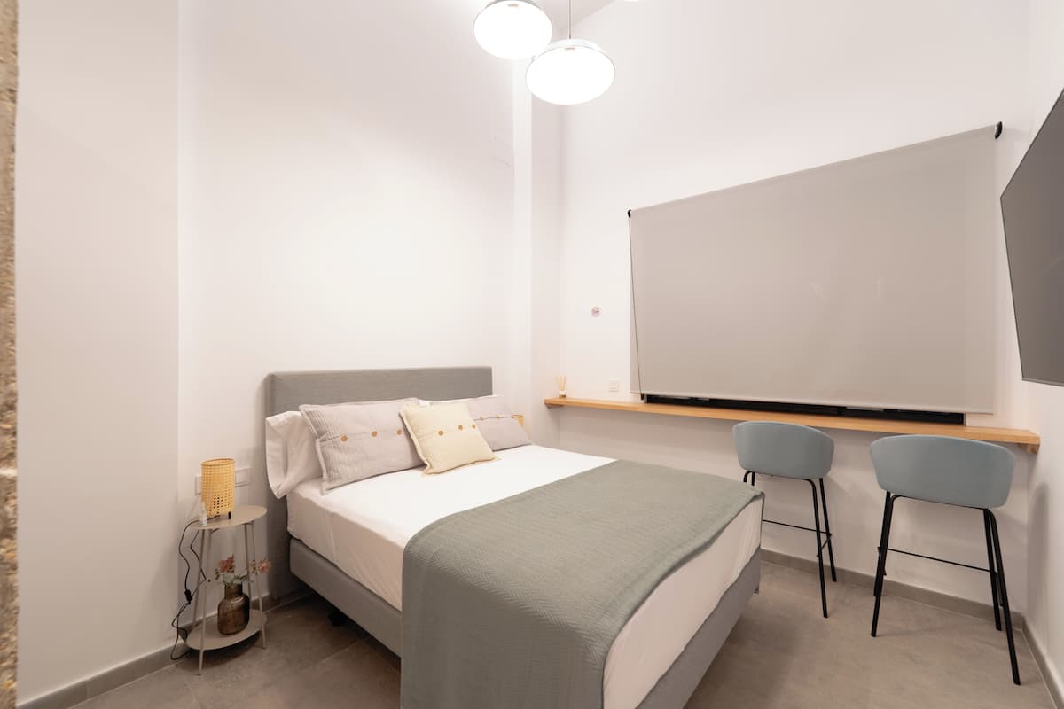 Ein modernes Schlafzimmer mit Bett, Nachttischen, Schreibtisch und zwei Stühlen.