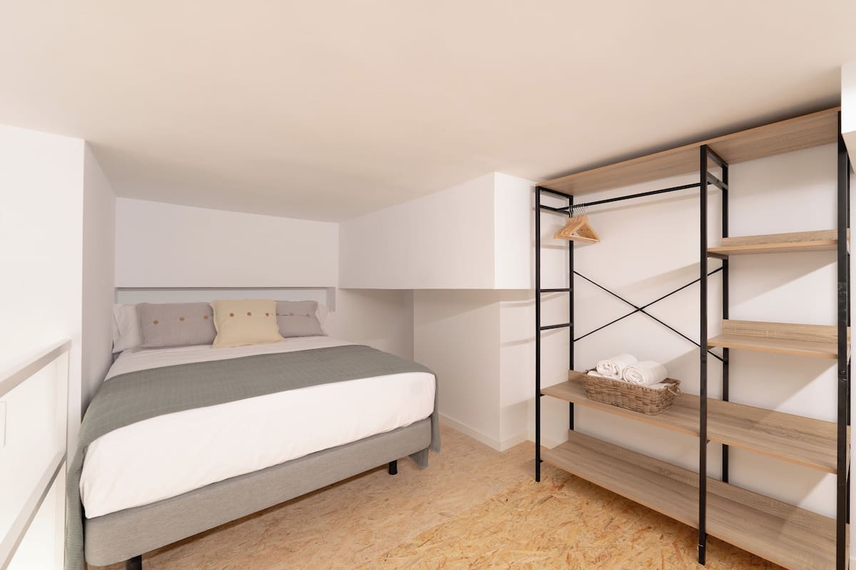 Ein gemütliches Schlafzimmer mit Bett, integriertem Kleiderschrank und Holzboden.