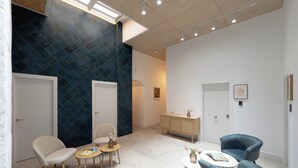 Un interior moderno con un diseño geométrico en la pared, un mueble de madera y varios arreglos de asientos.