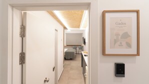 Un pasillo que conduce a una habitación con una obra de arte enmarcada en la pared y una puerta con cerradura moderna.