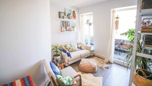 Un salon chaleureux avec un canapé, un fauteuil et un pouf, une bibliothèque ornée de photos encadrées et une plante en pot.