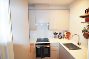A compact kitchen with a built-in oven, a sink, and a dishwasher.