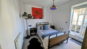Une chambre à coucher avec un lit, une table de chevet, une lampe et un tableau rouge accroché au mur.