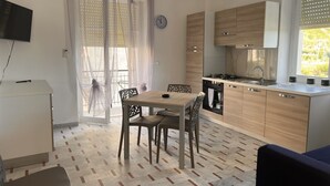Una cocina compacta con armarios de madera, una mesa de comedor con sillas y un televisor sobre un mueble.