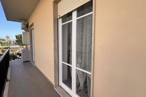 Parveke, josta avautuu näkymä puutarhaan ja kadun toisella puolella olevaan rakennukseen.