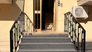 Un conjunto de escalones de hormigón que conducen a la entrada de un edificio, con barandillas de metal negro a ambos lados.