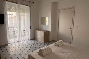 A bedroom with a bed, a dresser, a mirror, and a door. - Cozy and modern apartment a stone's throw from the sea (Marina di Fuscaldo)