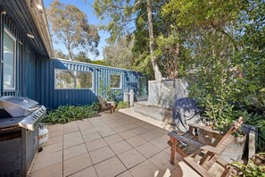 A blue house with a patio, a barbecue grill, and a wooden deck. - Cricklewood (Anglesea)