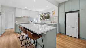 Een moderne keuken met een groot eiland, barstoelen en een koelkast.