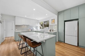 Eine moderne Küche mit einer großen Kochinsel, Barhocker und einem Kühlschrank.