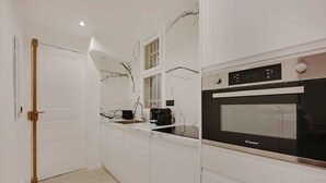 A modern kitchen with white cabinetry, a marble backsplash, and a Candy brand oven. - Charming Apartment - 2br/6p - Gare Saint-lazare (Paris)