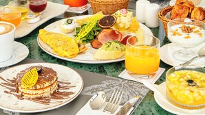 A breakfast buffet with various dishes, drinks, and a table setting with plates, glasses, and utensils. - NearYo Hotels (Marrakech)