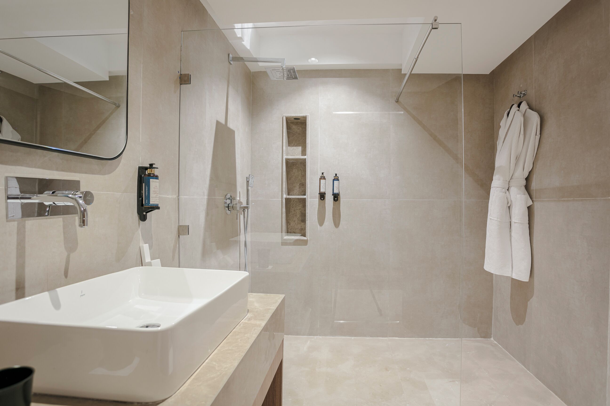 Un baño moderno con una bañera blanca grande, una ducha con mampara de vidrio y un perchero para toallas.