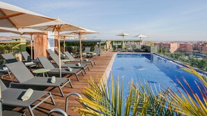 A rooftop pool area with lounge chairs and umbrellas, a clear view of the cityscape in the background. - NearYo Hotels (Marrakech)