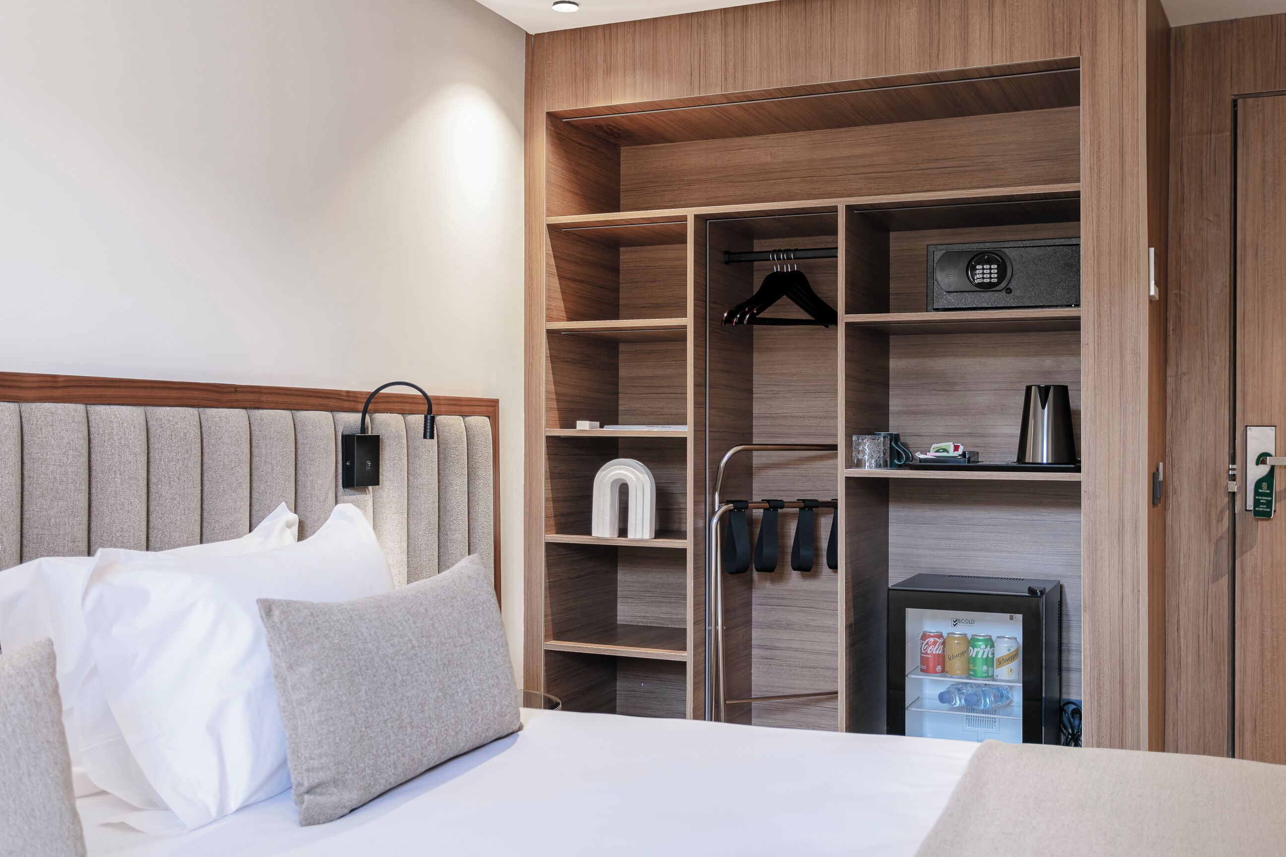 A hotel room with a bed, a wardrobe, and a minibar.