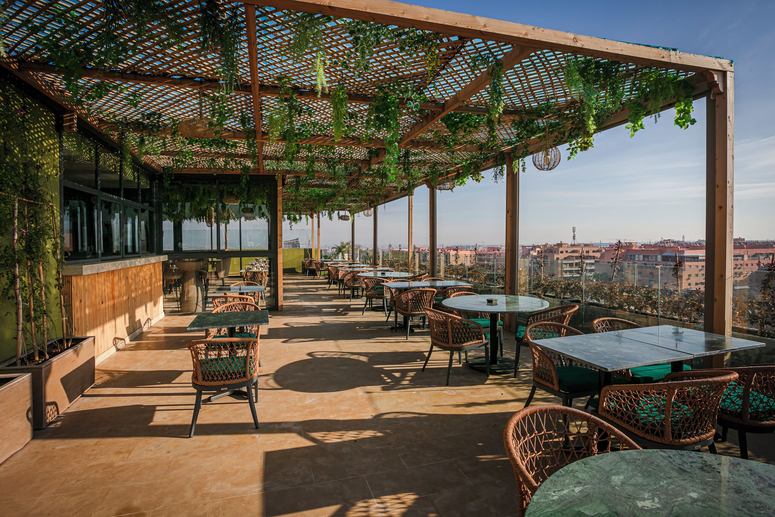 A rooftop terrace with outdoor seating, a bar area, and a view of the cityscape.