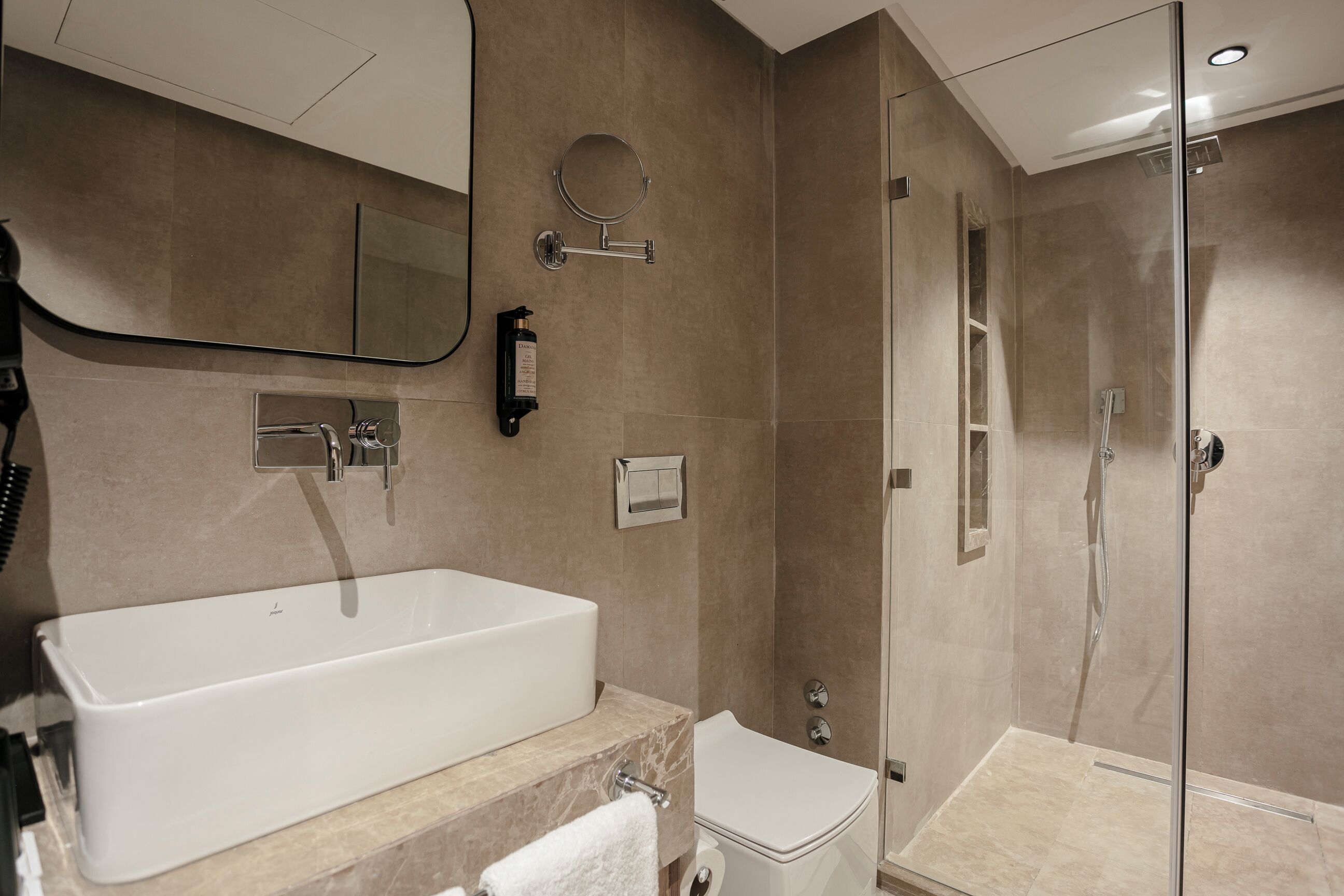 A modern bathroom with a large bathtub, a toilet, and a glass-enclosed shower area.