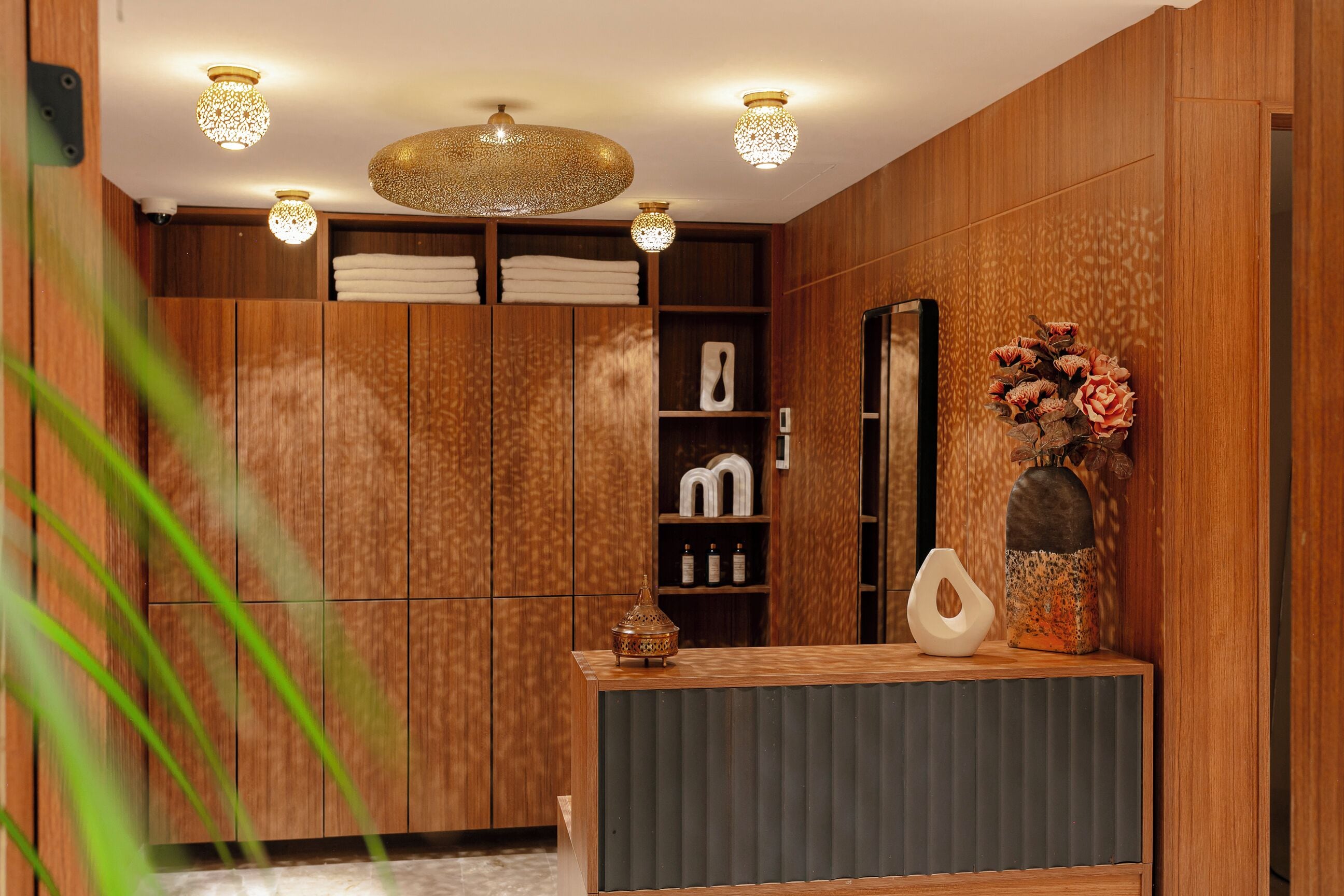 Un baño moderno con paneles de madera, un tocador con espejo e iluminación decorativa.
