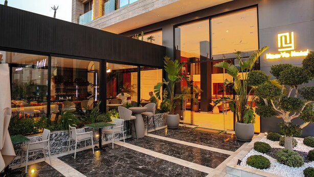 A hotel with outdoor seating, indoor dining, and a well-maintained garden. - NearYo Hotels (Marrakech)