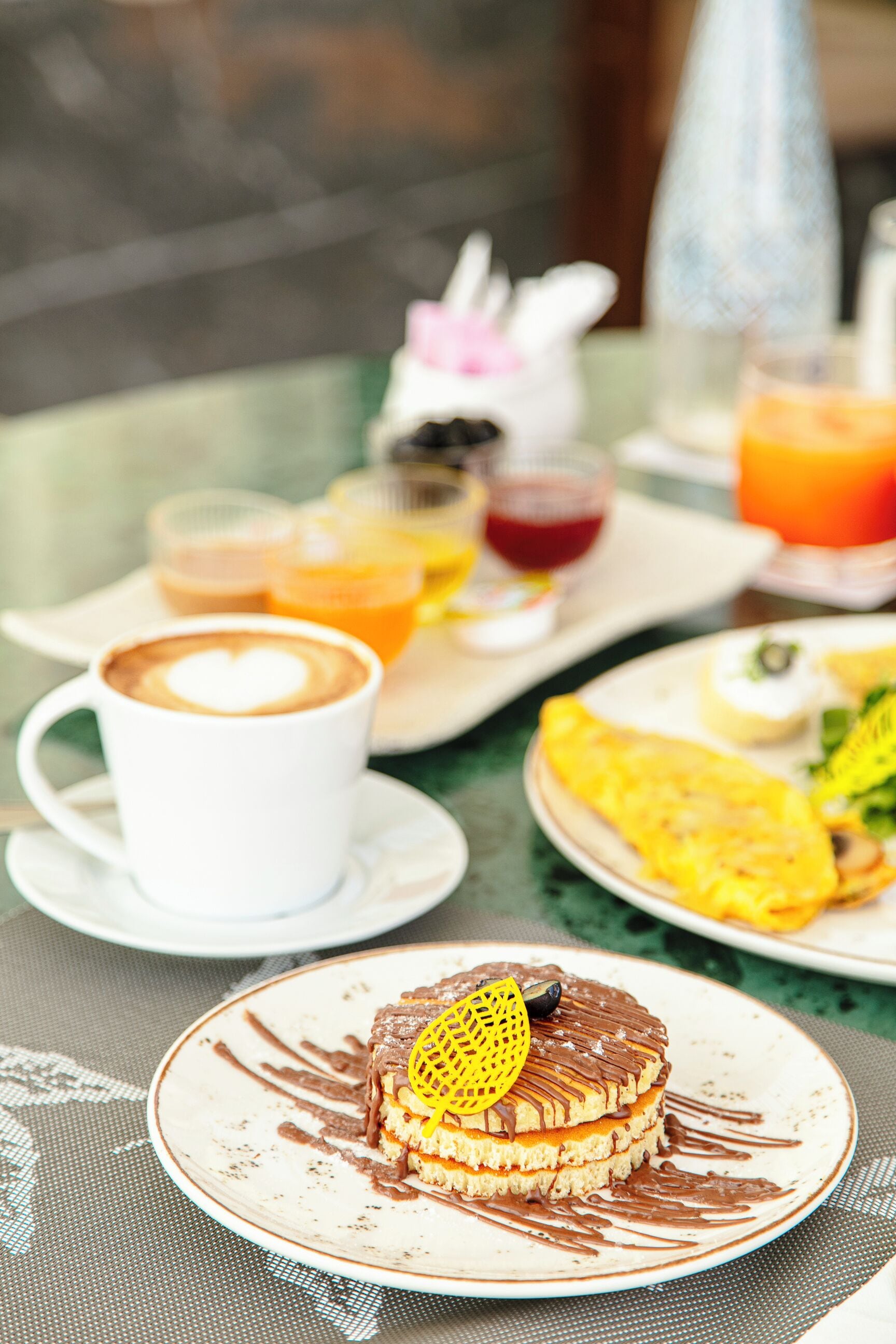 A breakfast setting with a plate of pancakes, a cup of coffee, and a glass of orange juice.