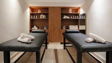 Ein Spa-Raum mit zwei Massagetischen, Holzböden mit Handtüchern und Pflegeprodukten sowie einem großen Holzschrank.