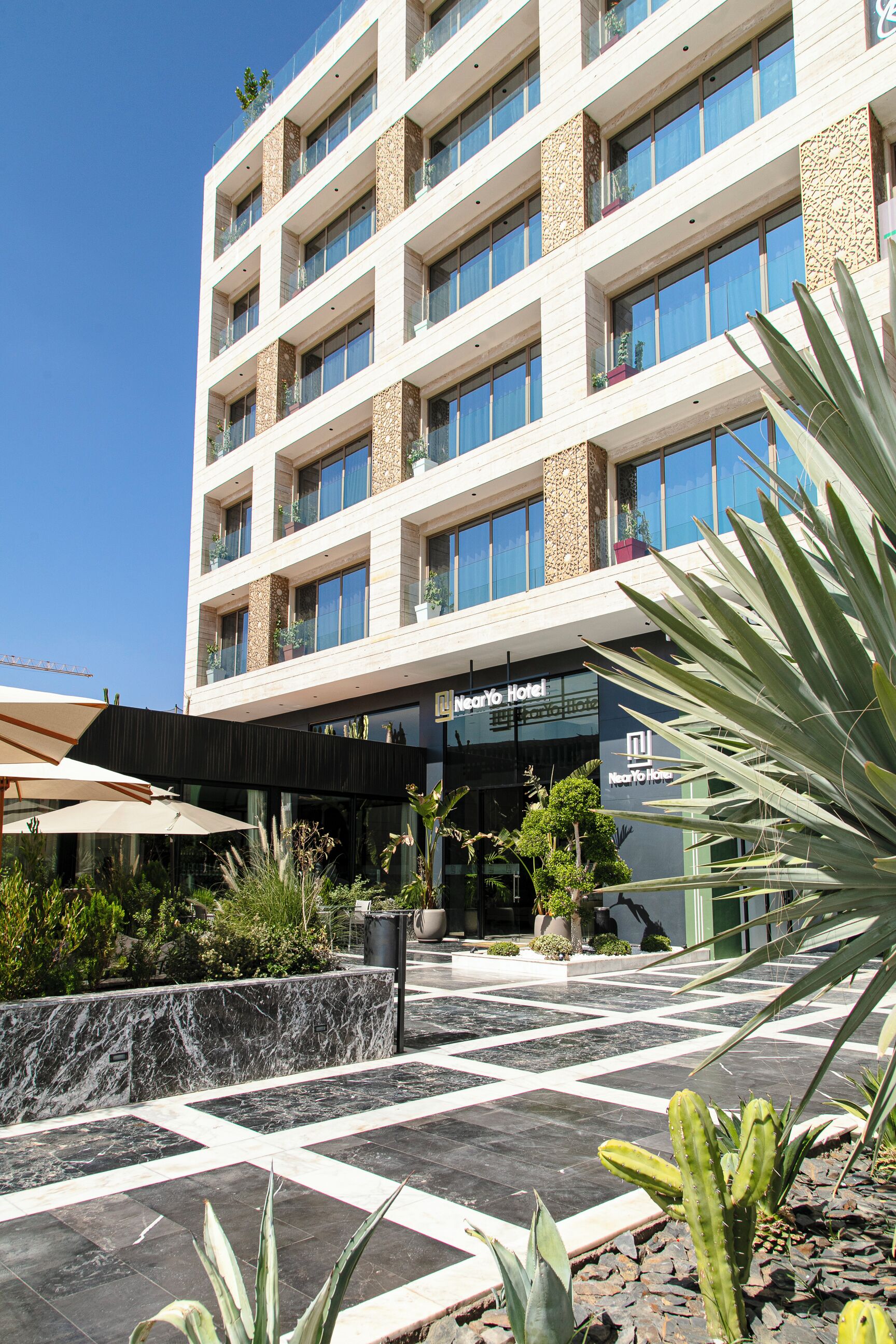 Un hotel de diseño moderno, con un patio con plantas y una zona cubierta.