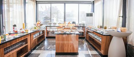 A modern breakfast buffet with a central island, wooden paneling, and a marble floor.