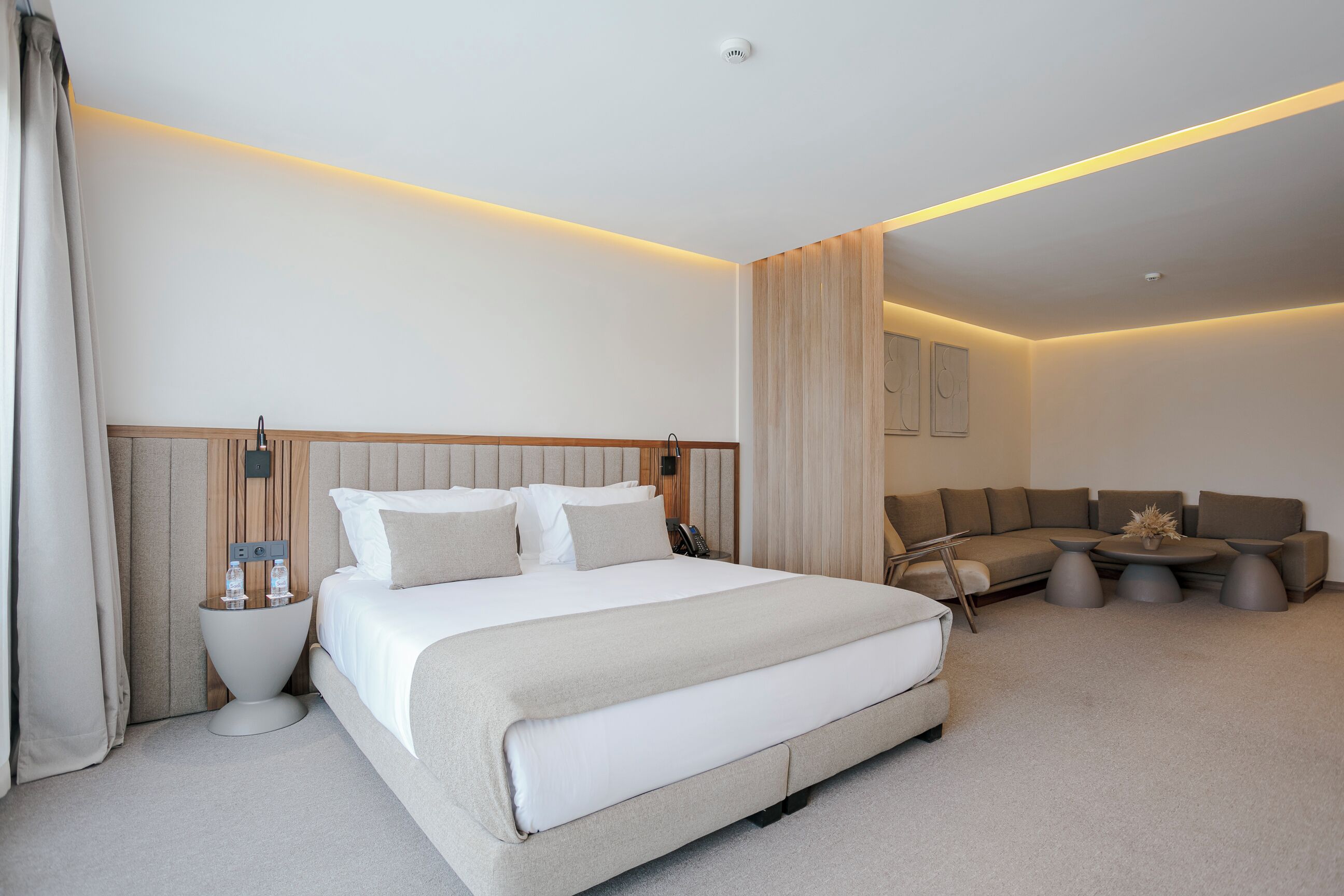 Une chambre d’hôtel moderne avec un grand lit, un canapé et une petite table basse.