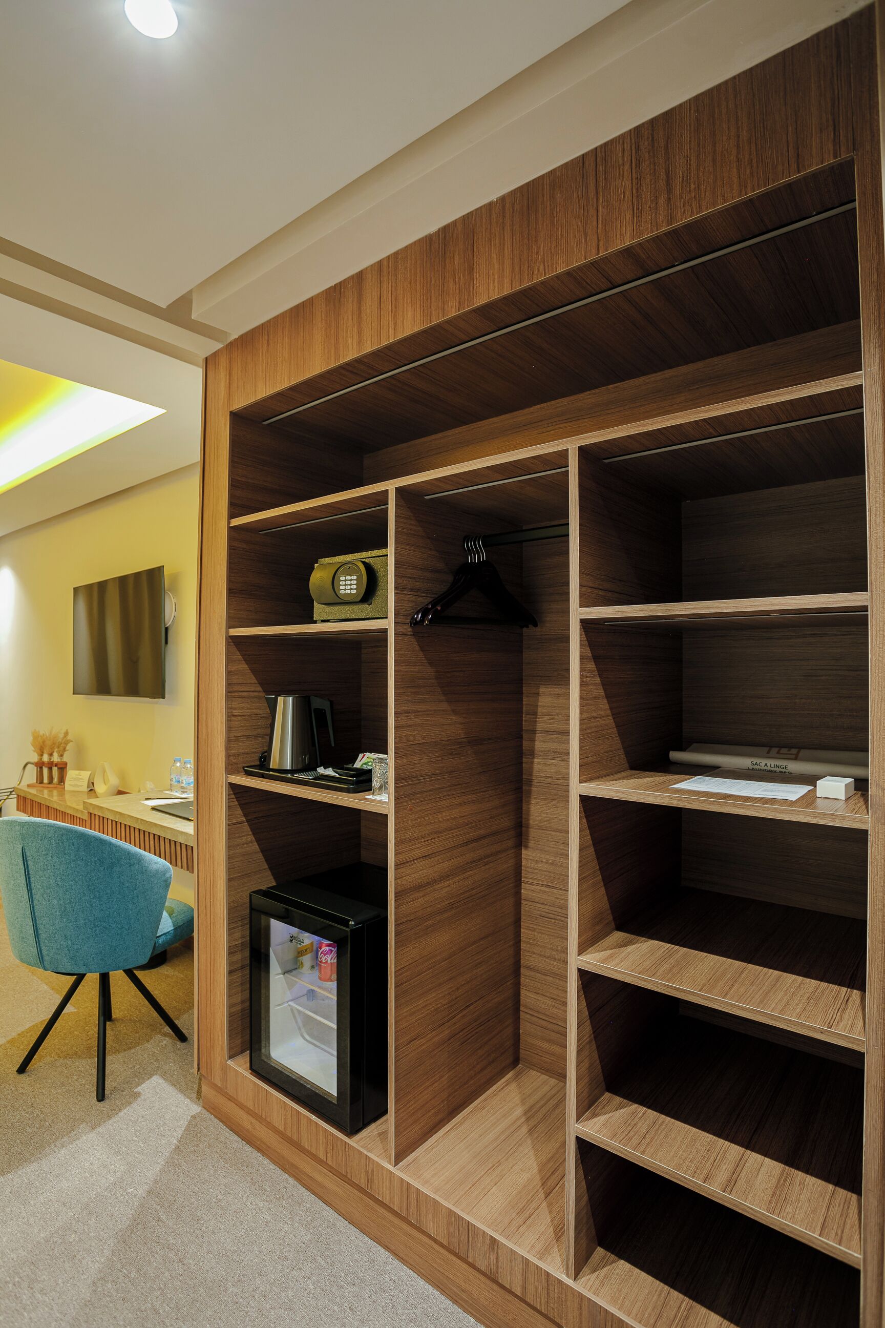 Habitación moderna con armario empotrado, un escritorio con silla y un refrigerador pequeño.