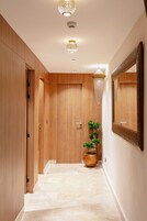 Un pasillo con puertas de madera, una planta en maceta y un espejo en la pared.
