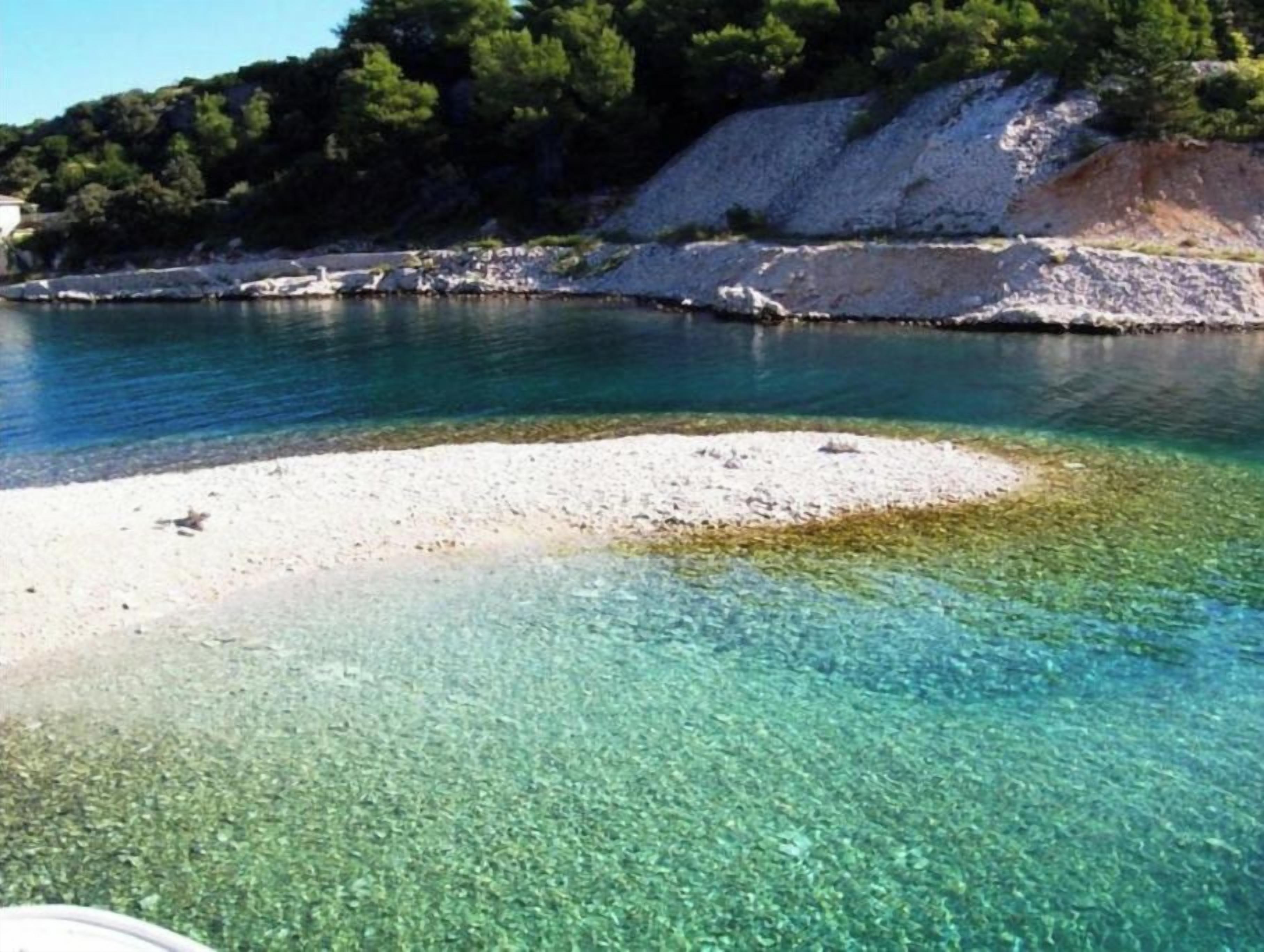 A clear coastal area with a sandy beach and calm water.