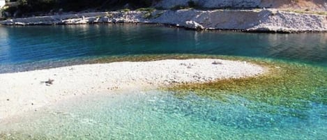 A clear coastal area with a sandy beach and calm water.