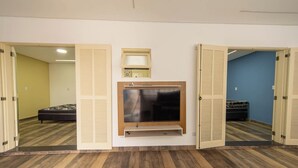 A hotel room with a bed, a TV mounted on the wall, and a mirror above it.