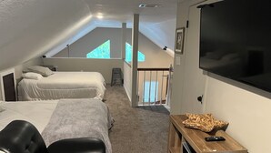 Een slaapkamer met twee bedden, een televisie en een houten dressoir.