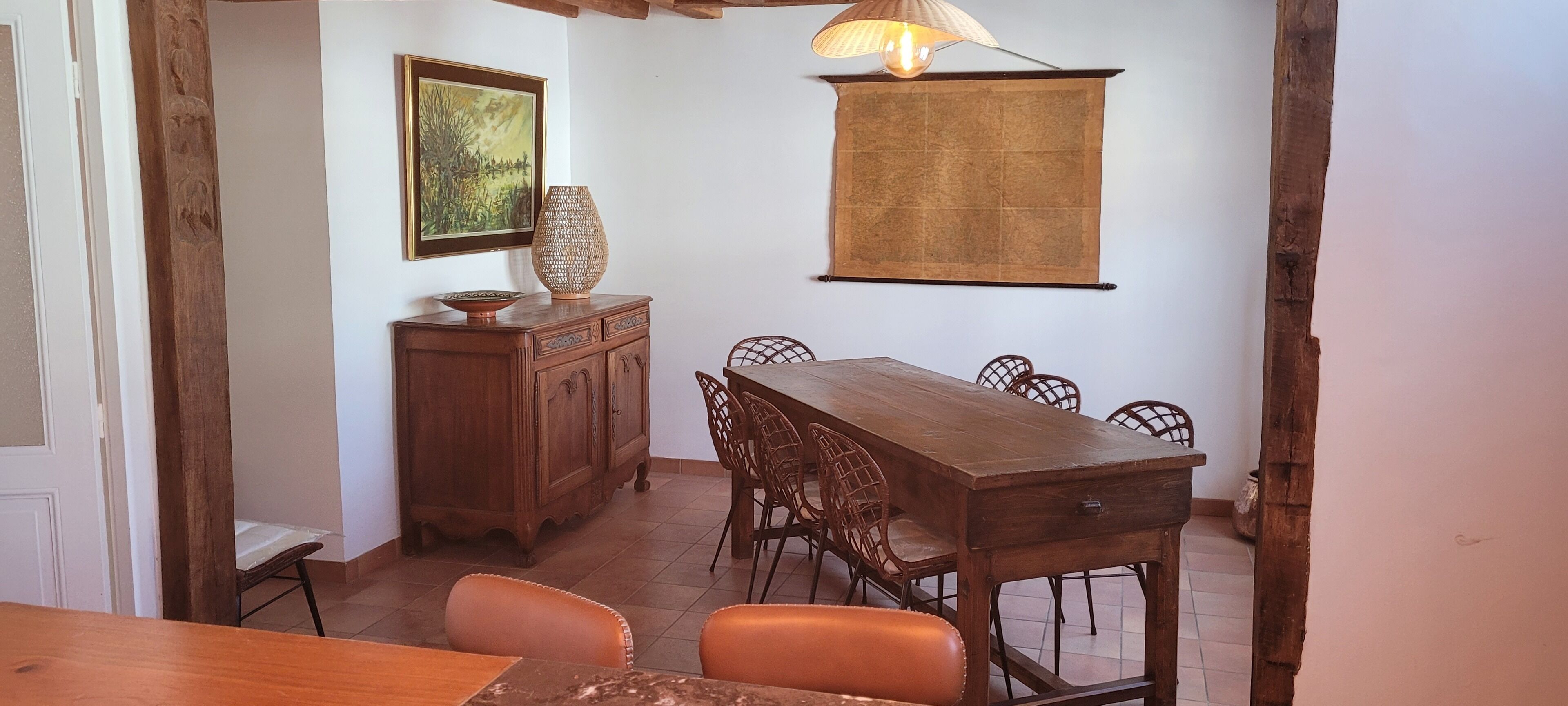 A dining area with a wooden table and chairs, a cabinet with decorative items, and a wall-mounted lamp.