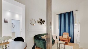 Una sala de estar moderna con un sofá verde, una mesa de centro redonda y una cortina azul.