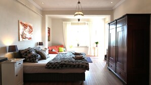 Un dormitorio con cama, mesita de noche, armario y ventana con cortinas.