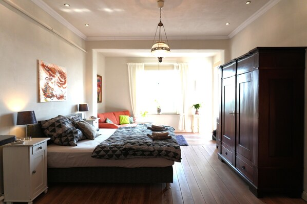 Une chambre à coucher comprenant un lit, une table de chevet, une armoire et une fenêtre avec des rideaux.